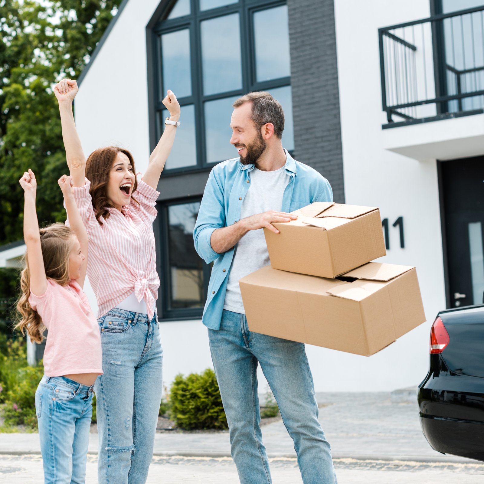 A family standing in front of a home on a tree-lined suburban street